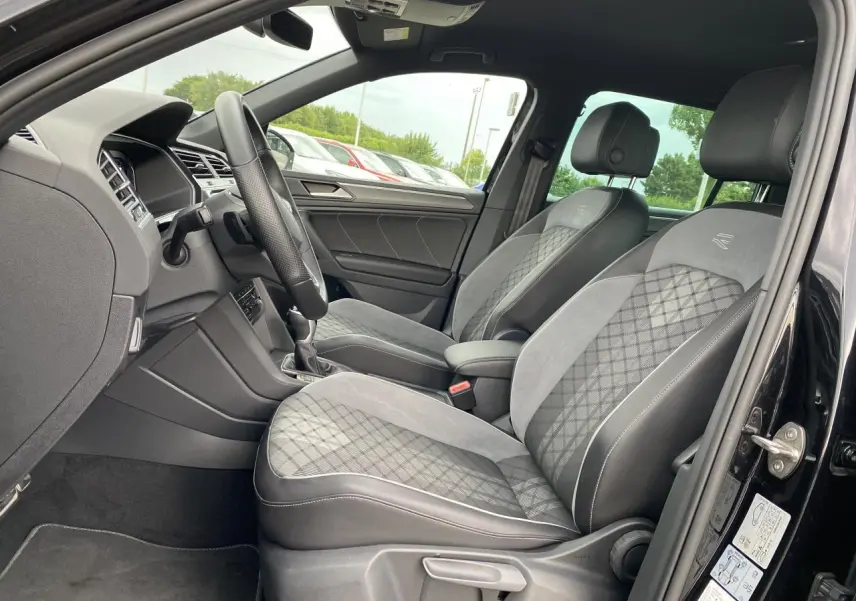 Intérieur avant du Volkswagen Tiguan 2023 noir intense, sièges sport en tissu et microfleece gris avec surpiqûres R-Line.