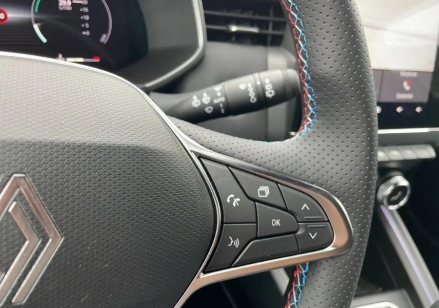Gros plan sur le volant perforé de la Renault Clio V TCE 90 Esprit Alpine 2025 avec surpiqûres tricolores bleu, blanc, rouge.