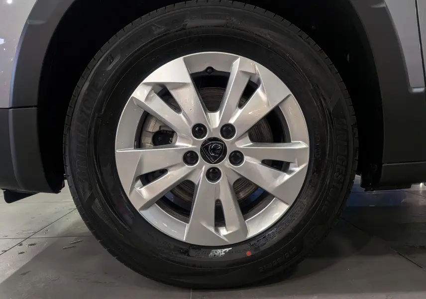 Gros plan sur la roue avant droite du Peugeot Rifter gris acier 2025 avec jante alliage et pneu Bridgestone.