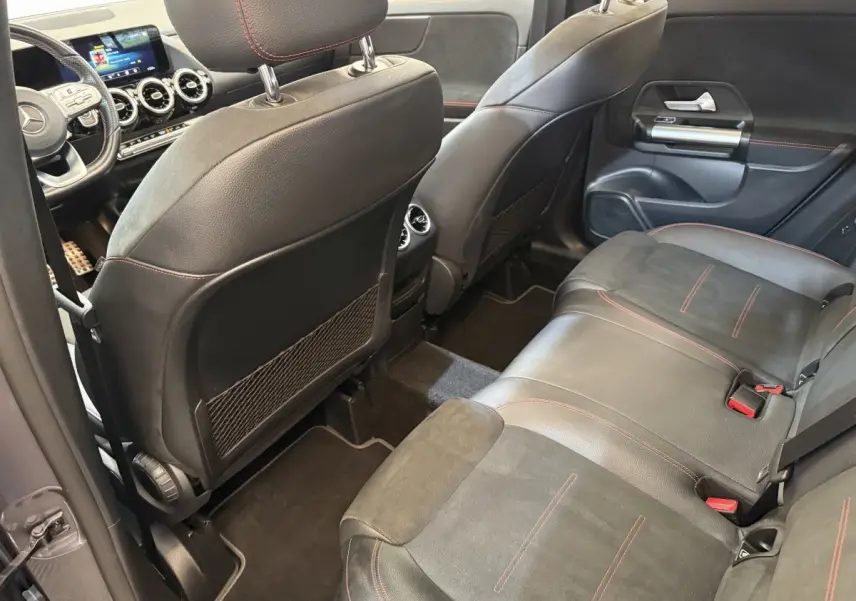 Vue intérieure arrière droite du Mercedes GLA 250 e AMG Line 2023, sièges cuir noir avec surpiqûres rouges et tableau de bord digital.