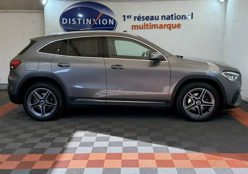 Vue de profil côté gauche d'une Mercedes GLA 250 e AMG Line hybride rechargeable gris clair, avec jantes alliage et rétroviseurs ton caisse.