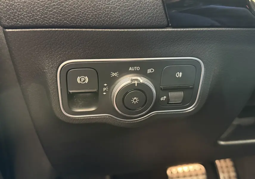 Détail du panneau de commande des phares et frein à main électrique sur tableau de bord noir du Mercedes GLA 250 e AMG Line.