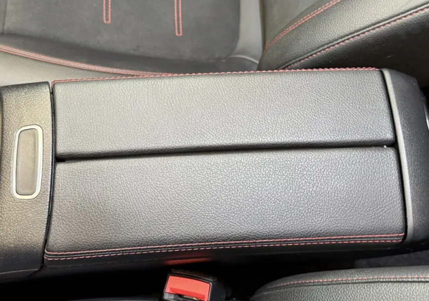 Gros plan sur l'accoudoir central en cuir noir avec surpiqûres rouges dans une Mercedes GLA 250 e AMG Line 2023.