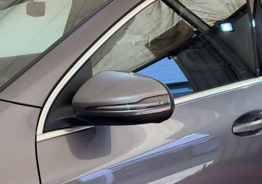Gros plan sur le rétroviseur côté gauche gris clair du Mercedes GLA 250 e AMG Line 2023 avec cadre de fenêtre chromé.
