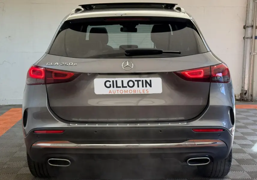 Vue arrière d'un Mercedes GLA 250 e AMG Line gris clair avec feux LED et double sortie d'échappement chromée.