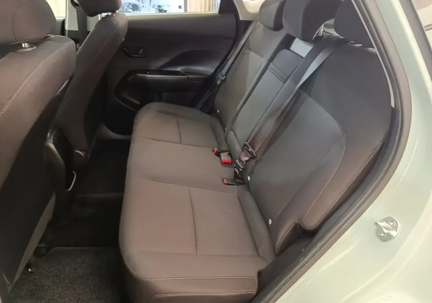Vue intérieure côté droit montrant la banquette arrière noire du Hyundai Kona 2024 vert, avec ceinture de sécurité attachée.
