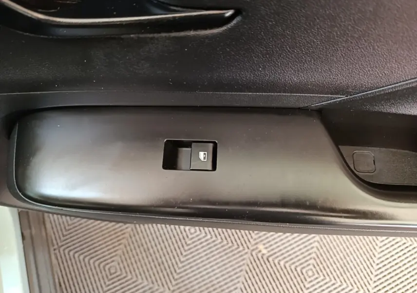 Gros plan sur le bouton de commande de la vitre électrique côté conducteur d’un Hyundai Kona vert 2024.