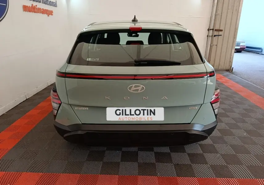 Vue arrière d'une Hyundai Kona hybride 2024 vert clair avec feux arrière LED en bandeau et logo central.