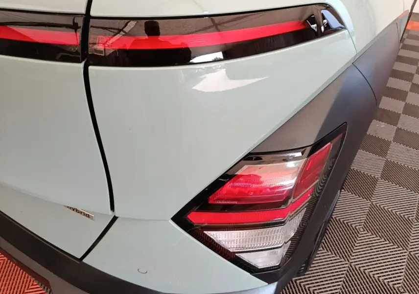 Gros plan sur le feu arrière droit et la partie arrière verte du Hyundai Kona 1.6 Hybrid 2024 avec bandeau lumineux rouge.