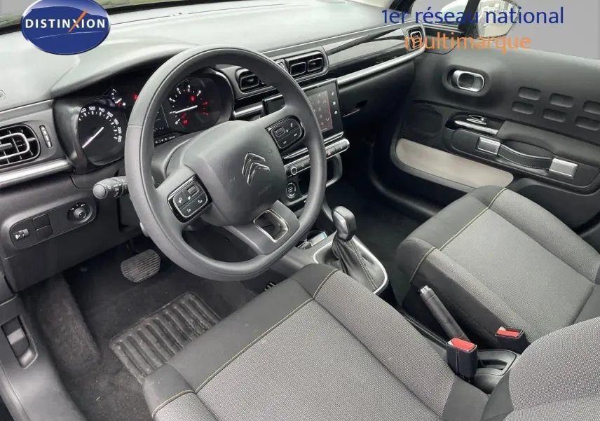 Intérieur de la Citroën C3 2023 en tissu gris, vue côté conducteur montrant tableau de bord et volant multifonction.