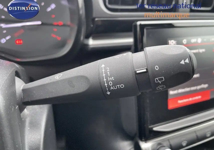 Gros plan sur la commande d'essuie-glace à gauche du volant dans l'habitacle d'une Citroën C3 noire 2023.