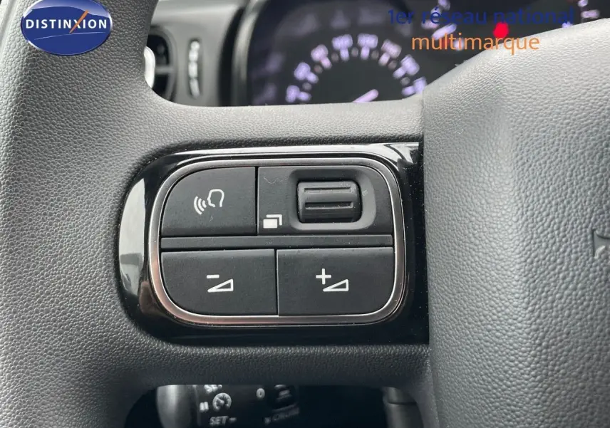 Gros plan sur les commandes de volume et de téléphone au volant d'une Citroën C3 noire métal 2023.