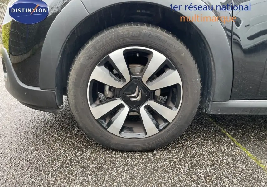 Gros plan sur la roue avant gauche d'une Citroën C3 noire métal avec jante alliage bicolore.