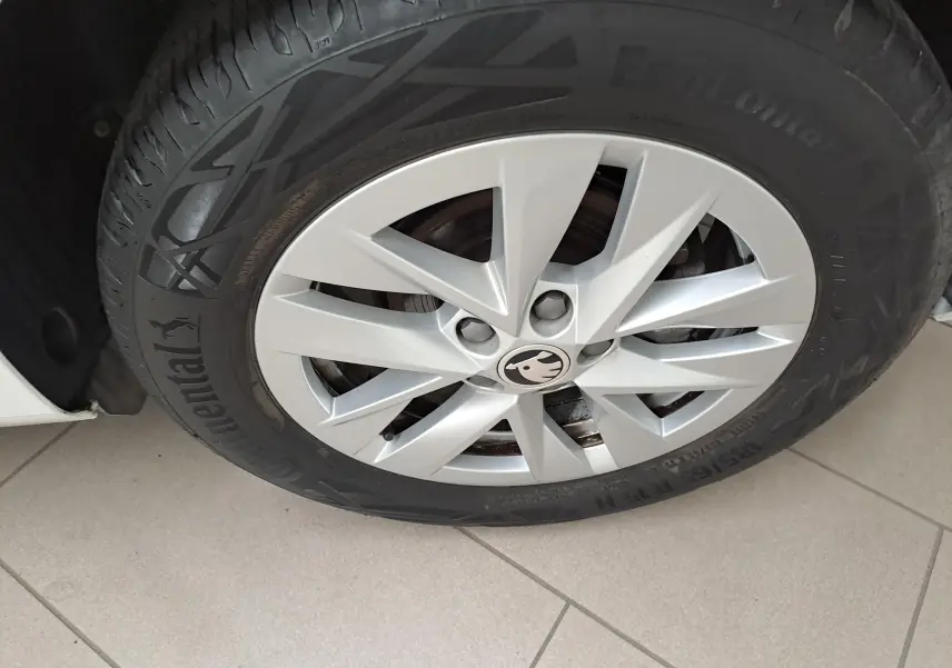 Gros plan sur la roue avant gauche d'une Skoda Fabia blanche 2023 avec jante en alliage et logo Skoda central.