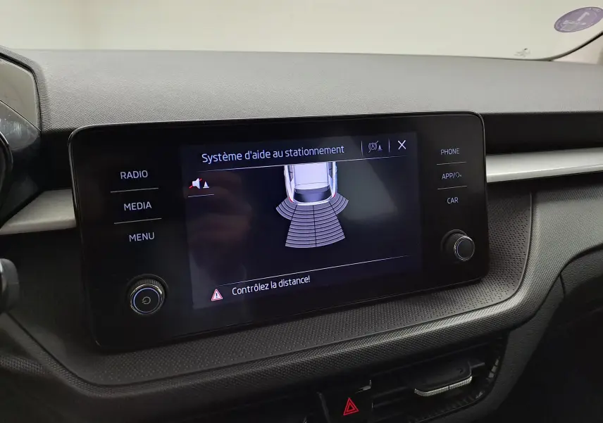 Écran central du système d'aide au stationnement dans une Skoda Fabia blanche 2023, tableau de bord moderne.
