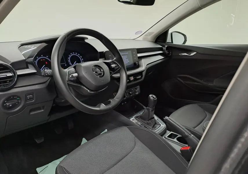 Intérieur noir de la Skoda Fabia 2023, vue côté conducteur montrant le volant, tableau de bord et levier de vitesses manuel.