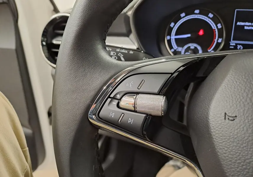 Gros plan sur les commandes gauche du volant de la Skoda Fabia 2023, finition Ambition, avec tableau de bord en arrière-plan.