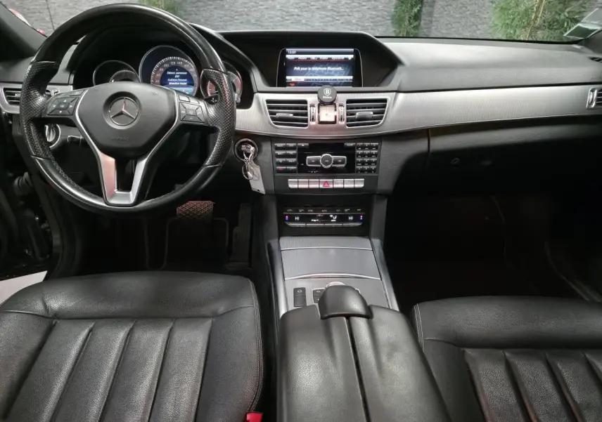 Intérieur noir de la Mercedes Classe E 300 BlueTEC Hybrid 2015, vue frontale sur tableau de bord et volant cuir.