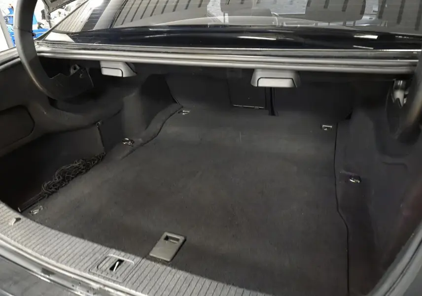 Coffre ouvert d'une Mercedes Classe E noire, vue intérieure montrant un espace de chargement propre et spacieux.