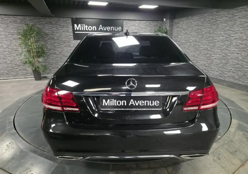 Vue arrière d'une Mercedes Classe E noire avec feux arrière rouges et double sortie d'échappement trapezoïdale.