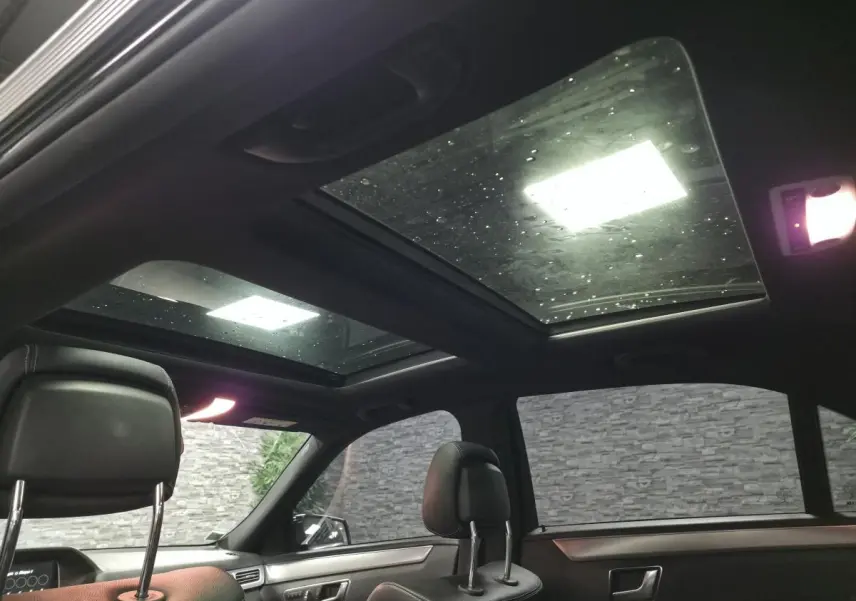 Vue intérieure du toit ouvrant panoramique vitré de la Mercedes Classe E 300 BlueTEC Hybrid noire de 2015.