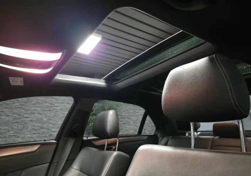 Intérieur noir de la Mercedes Classe E 300 BlueTEC Hybrid 2015 avec toit ouvrant vitré et sièges avant en cuir.