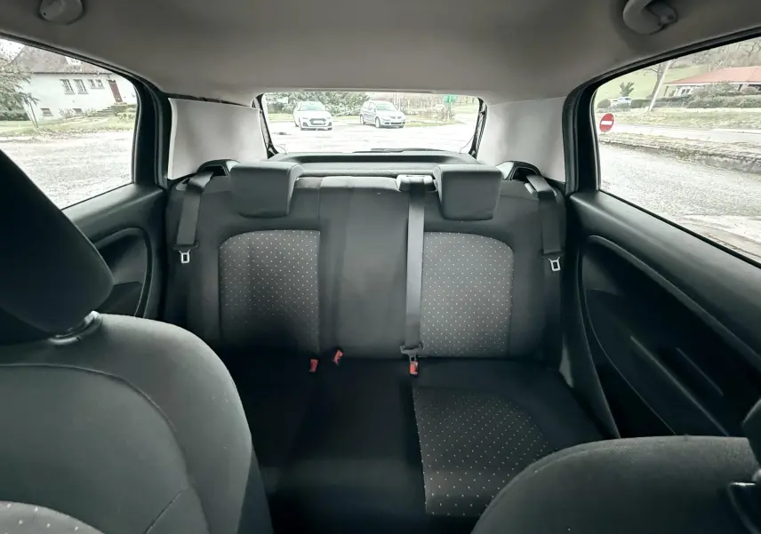 Vue intérieure arrière montrant les sièges noirs avec motifs à petits points du Fiat Punto 1.2 i 65 de 2009.