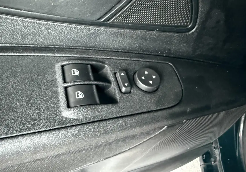 Gros plan sur les commandes de lève-vitres et réglage des rétroviseurs côté conducteur d'une Fiat Punto noire de 2009.