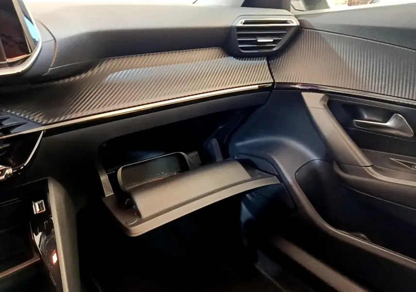 Intérieur de la Peugeot 2008 2021, vue côté passager, tableau de bord noir avec boîte à gants ouverte.
