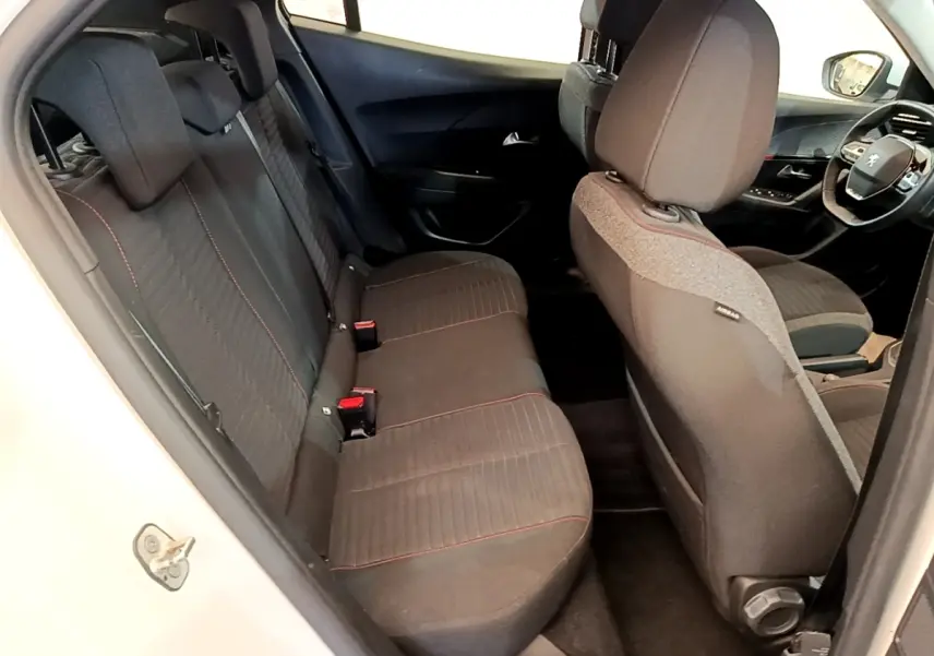 Vue intérieure côté gauche montrant les sièges arrière noirs avec surpiqûres rouges d’un Peugeot 2008 blanc.