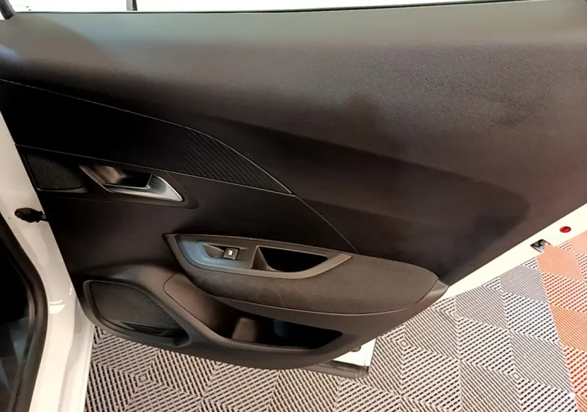Vue intérieure de la porte avant gauche du Peugeot 2008 blanc, avec commande de lève-vitre et habillage noir.