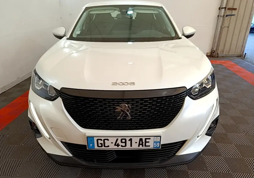 Vue avant d’un Peugeot 2008 blanc avec calandre noire et feux LED, immatriculé en France, dans un garage.