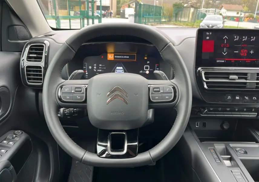 Vue frontale de l'intérieur du Citroën C5 Aircross Hybrid 145, volant cuir multifonctions et écran tactile central.