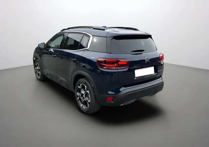 Vue 3/4 arrière droite d'un Citroën C5 Aircross Hybrid 145 Eclipse Blue avec barres de toit et jantes alu 18 pouces.