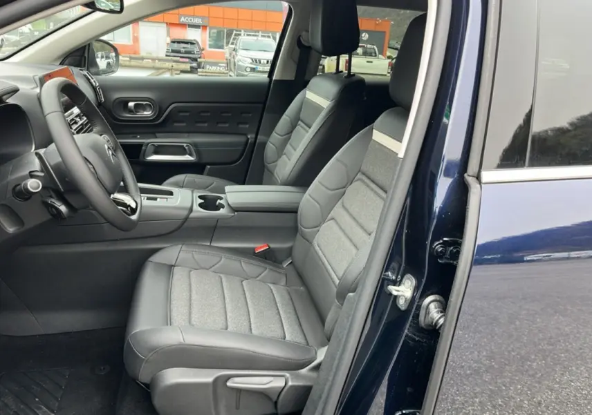 Vue intérieure côté conducteur du Citroën C5 Aircross Hybrid 145 en Eclipse Blue, sièges confort bi-matière gris et noir.