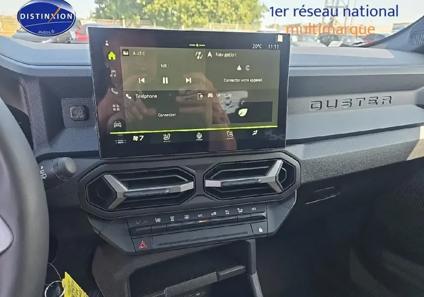 Vue intérieure du tableau de bord du Dacia Duster 2025 avec écran tactile et aérateurs hexagonaux noirs.
