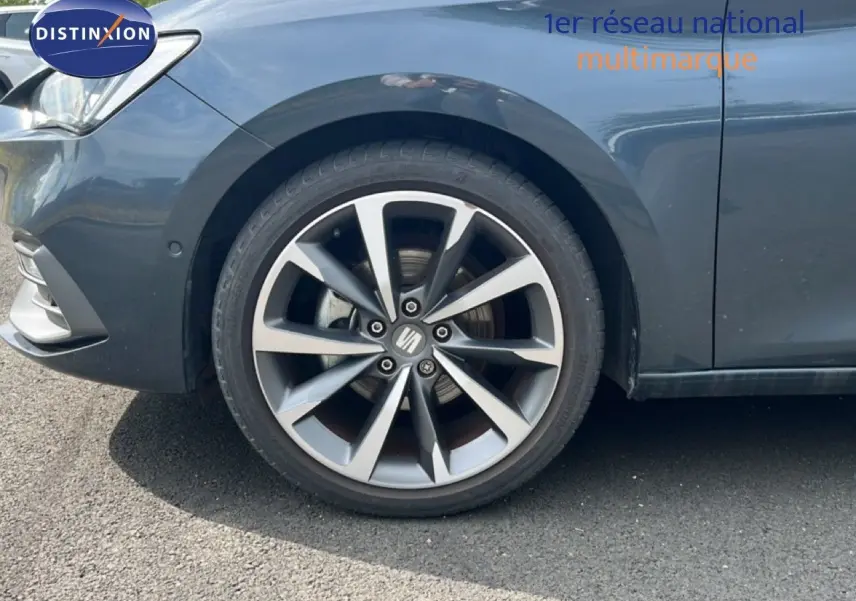 Gros plan sur la roue avant gauche d'une SEAT LEON ST gris magnétique métal, avec jante alliage à dix branches.