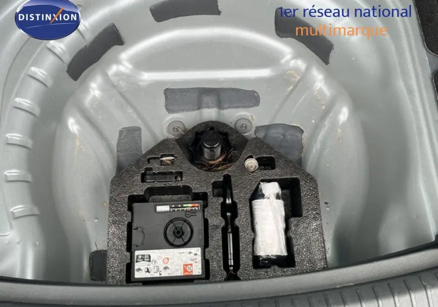 Vue plongeante sur le rangement gris métallique du kit de réparation de roue dans le coffre d'une SEAT LEON ST 2025.