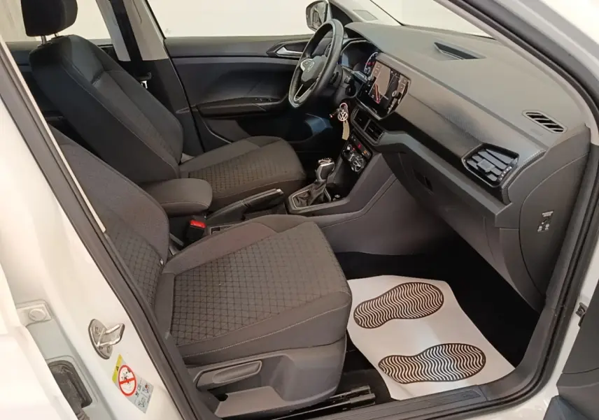 Vue intérieure côté conducteur du Volkswagen T-Cross blanc 2022, montrant sièges tissu noirs et tableau de bord moderne.