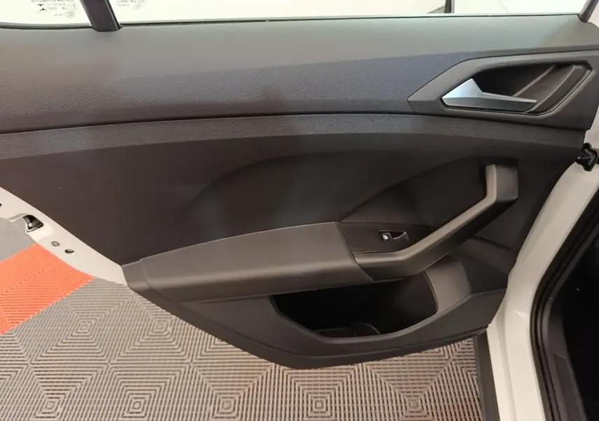 Vue intérieure de la porte avant droite noire du Volkswagen T-Cross blanc, avec poignée et bouton de lève-vitre.