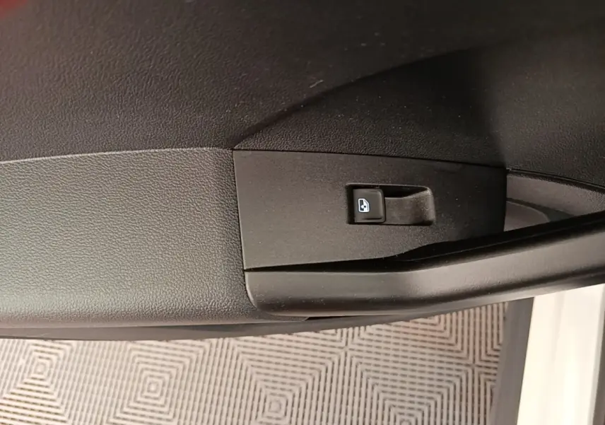 Gros plan sur la commande de verrouillage des portes intégrée à la portière côté conducteur d’un Volkswagen T-Cross blanc.