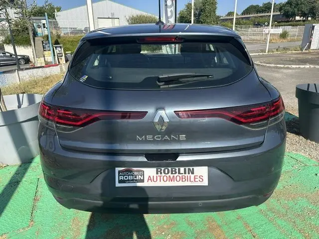 Vue arrière d'une Renault Mégane bleu foncé 2021 avec feux LED et logo central sur un parking extérieur.