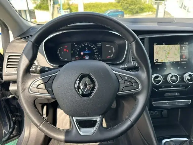 Vue intérieure centrée sur le volant noir de la Renault Mégane 1.5 Blue dCi 115ch Business avec tableau de bord numérique et écran GPS tactile.