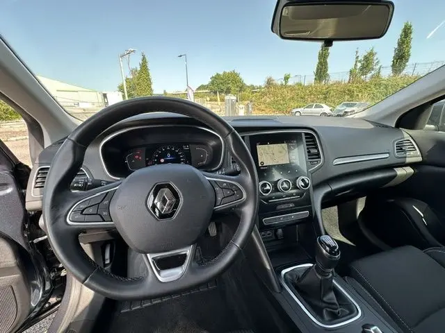 Vue intérieure de face du poste de conduite d'une Renault Mégane 1.5 Blue dCi 115ch Business 2021 avec volant multifonction et écran tactile.