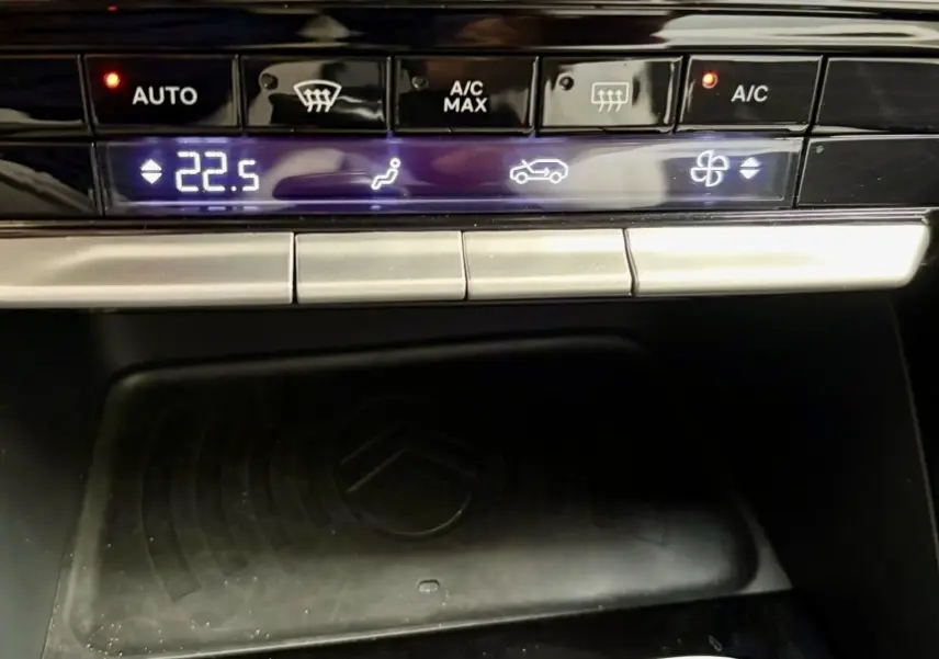 Vue rapprochée de la console centrale noire du Citroën C3 2025, affichant la climatisation et la zone de recharge sans fil.
