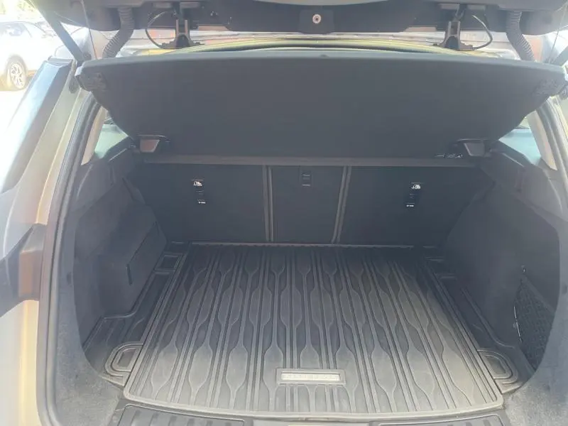 Coffre ouvert du Range Rover Evoque Indus Silver, montrant le tapis de coffre noir texturé et la plage arrière relevée.