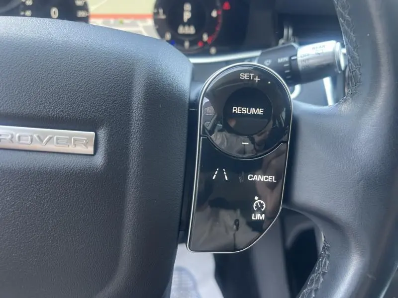 Gros plan sur les commandes au volant cuir noir du Range Rover Evoque Indus Silver, avec régulateur de vitesse et assistance de trajectoire.