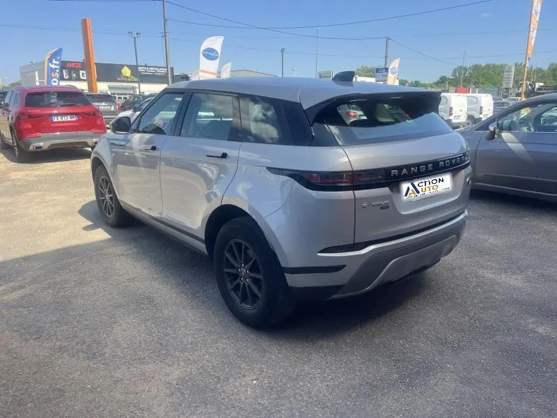 Vue 3/4 arrière droite d'un Range Rover Evoque Indus Silver avec jantes noires et becquet arrière visible.