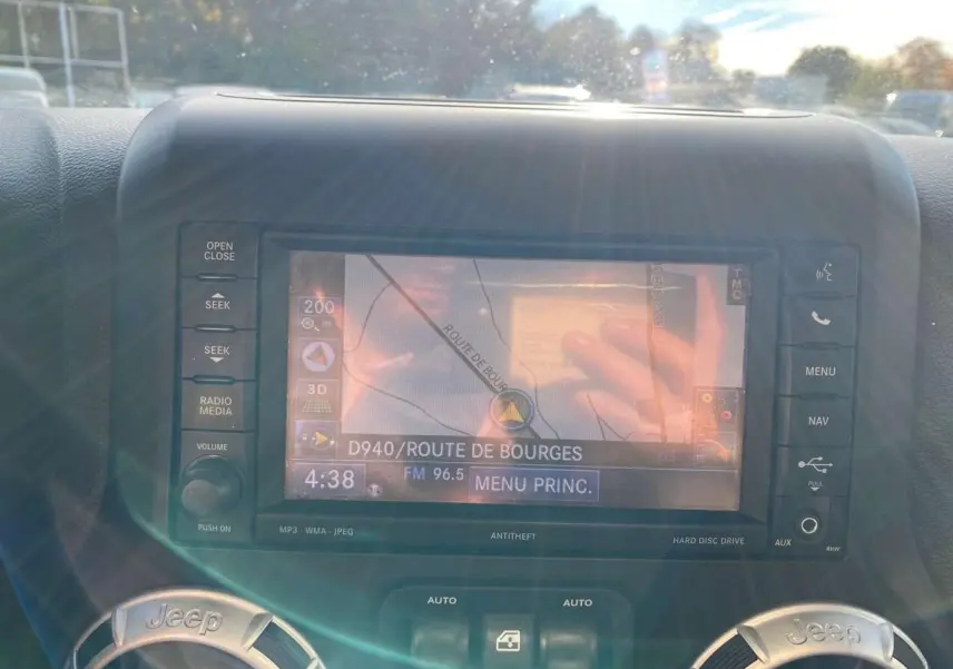 Écran de navigation central du Jeep Wrangler gris clair 2012, affichant une carte et les commandes environnantes.