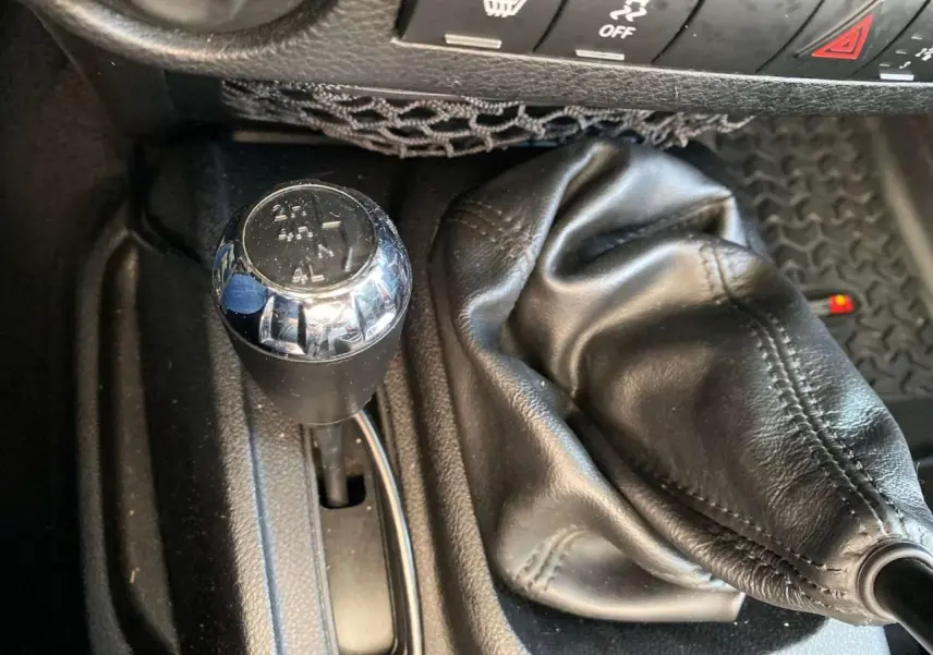 Gros plan sur le levier de vitesses manuel et la commande de boîte de transfert du Jeep Wrangler gris clair 2012.
